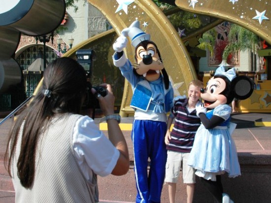 Een Disney-fotograaf zet een jonge bezoeker op de foto samen met Goofy en Minnie - Foto: (c) Disney
